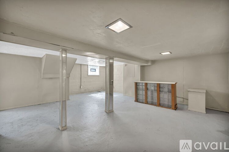 A spacious empty room with a white ceiling and walls, a door, and a window.