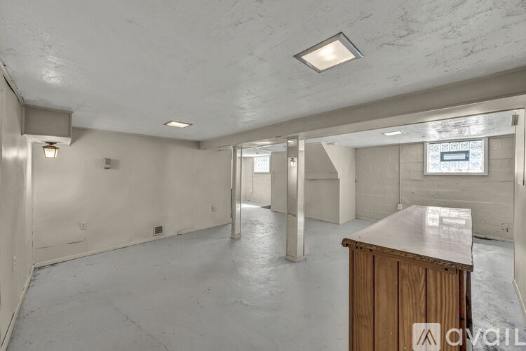 A large empty room with a wooden cabinet in the foreground.