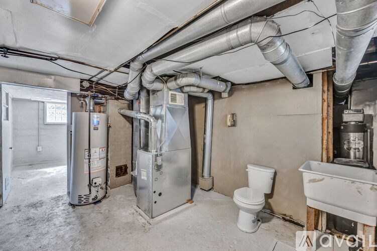 A room with a toilet, a sink, and a large metal pipe running along the ceiling.