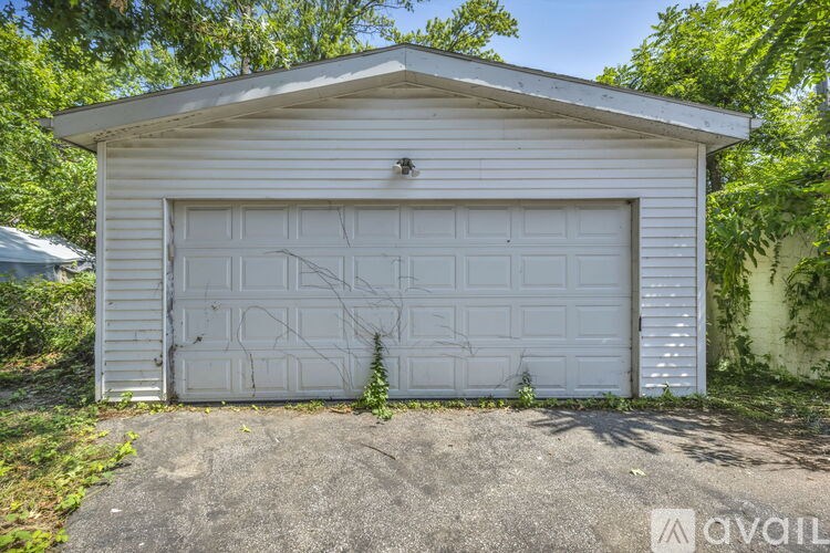 A white garage door is closed and has a small plant growing out of it.