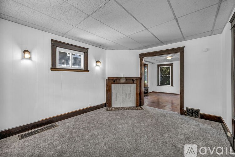 A room with a white wall and a window with a brown frame.