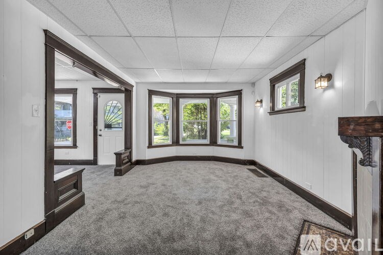 A spacious room with a carpeted floor and large windows.