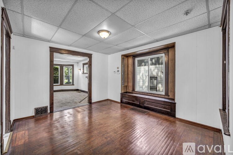 A room with wooden floors and white walls, with a mirror on the left side.