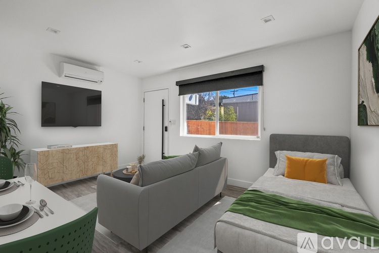 A modern bedroom with a grey couch, a bed, and a television.