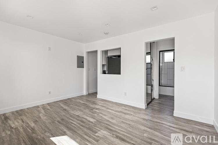 A spacious room with wood flooring and white walls.