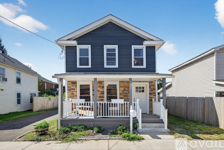 A two-story house with a porch and a white picket fence.