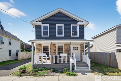 A two-story house with a porch and a white picket fence.