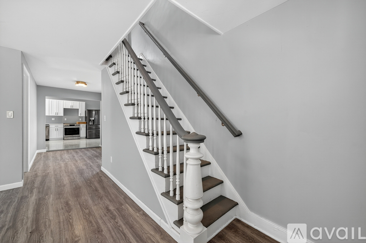 A staircase with a wooden handrail and steps leading to a kitchen area.