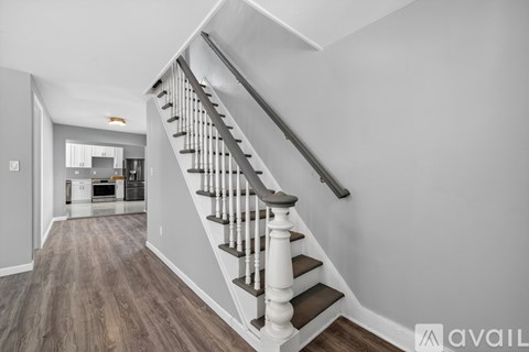 A staircase with a wooden handrail and steps leading to a kitchen area.