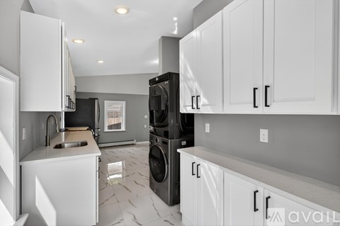 A kitchen with white cabinets and a black refrigerator.