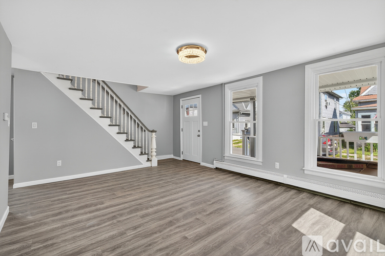 A spacious living room with a staircase and a view of the outside.