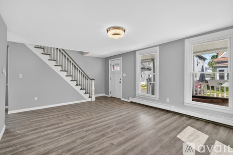 A spacious living room with a staircase and a view of the outside.