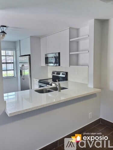 A kitchen with white countertops and stainless steel appliances.