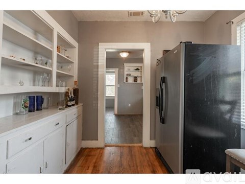 A kitchen with white cabinets and a black fridge.