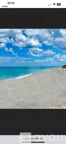 A beach with white sand and blue water under a cloudy sky.