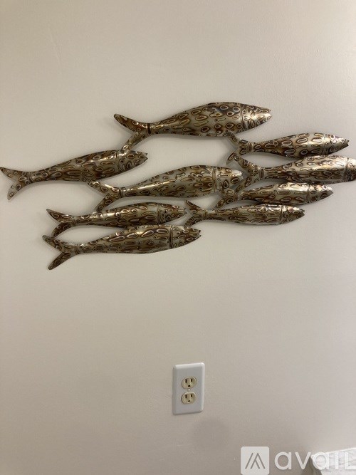 A wall decoration of fish is above a light switch.