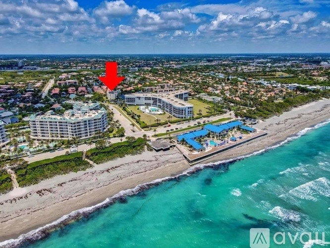 An aerial view of a beachfront property with a red arrow pointing to a specific area.