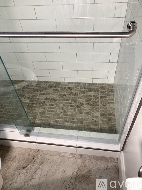 A glass shower door with a silver handle.