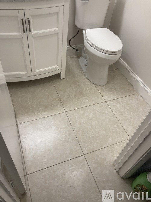 A white toilet in a bathroom with a white cabinet.