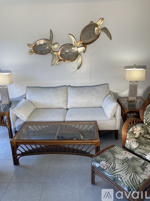A living room with a white couch, a wooden coffee table, and a wall decoration of three turtles.