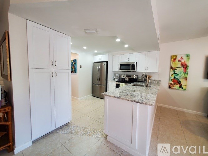 A kitchen with white cabinets and a marble countertop.