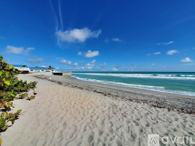 A beach with a clear blue sky and white clouds.