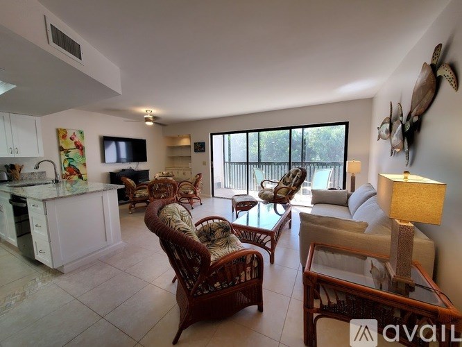 A living room with a white kitchen area and a flat screen TV.