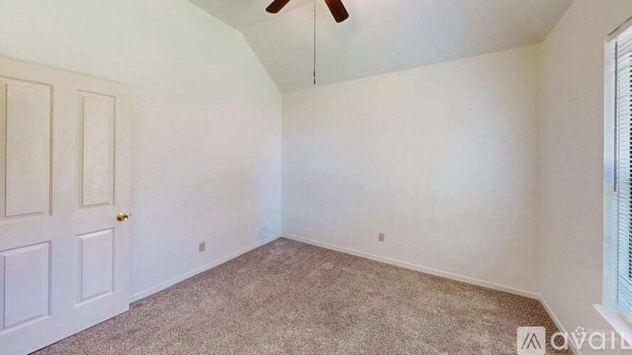 A room with a carpeted floor and a ceiling fan.