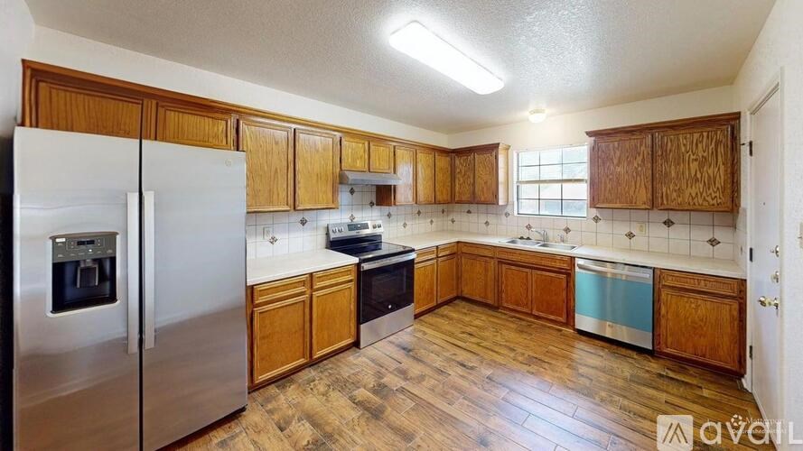 A kitchen with wooden cabinets and a stainless steel refrigerator.