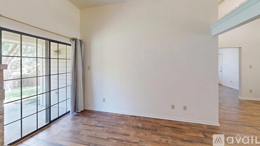 A room with wooden flooring and a large window with a view of trees.