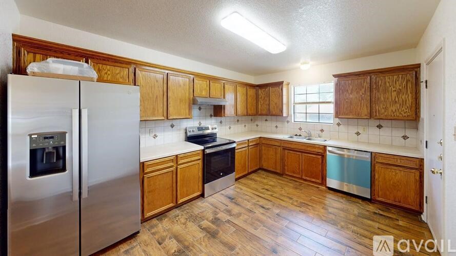 A kitchen with wooden cabinets and a stainless steel refrigerator.