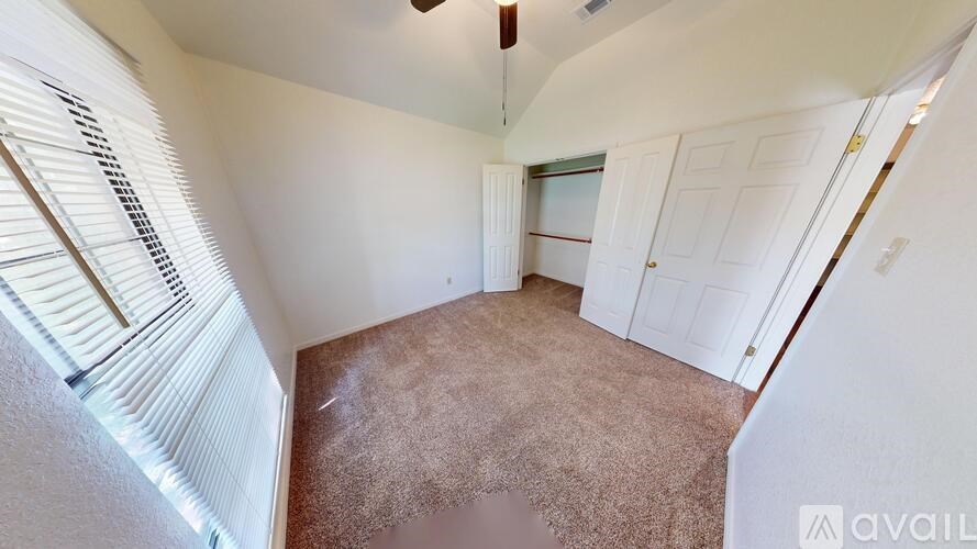 A room with a carpeted floor and a window with blinds.