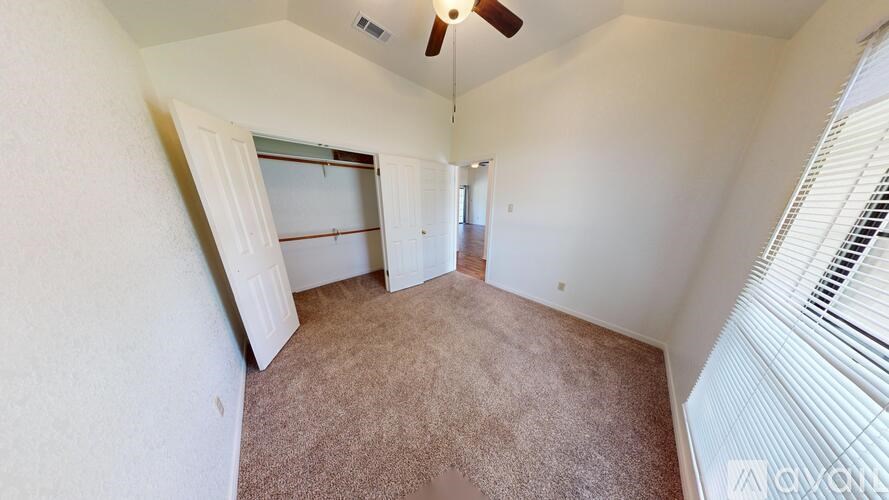 A room with a ceiling fan and carpeted floor.