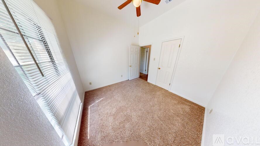 A room with a fan and a carpeted floor.