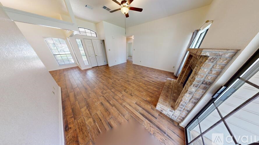A spacious living room with wood flooring and a fireplace.