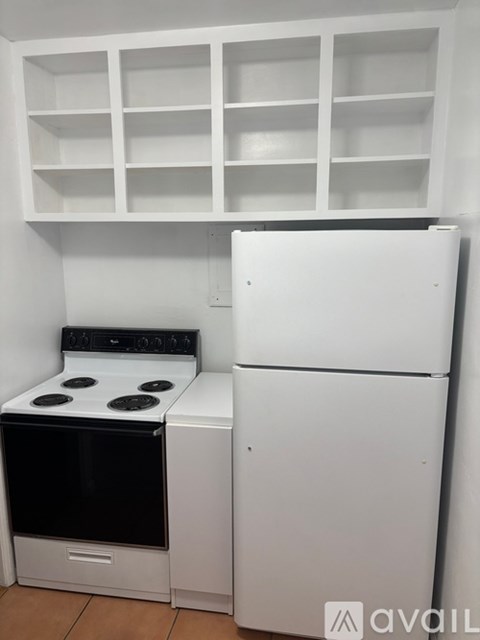 A white kitchen with a stove and a refrigerator.