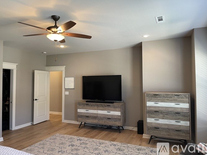 A room with a television and a fan on the ceiling.