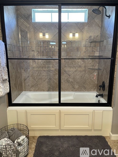 A bathroom with a large glass shower door and a bathtub.