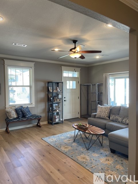 A living room with a grey couch and a wooden floor.