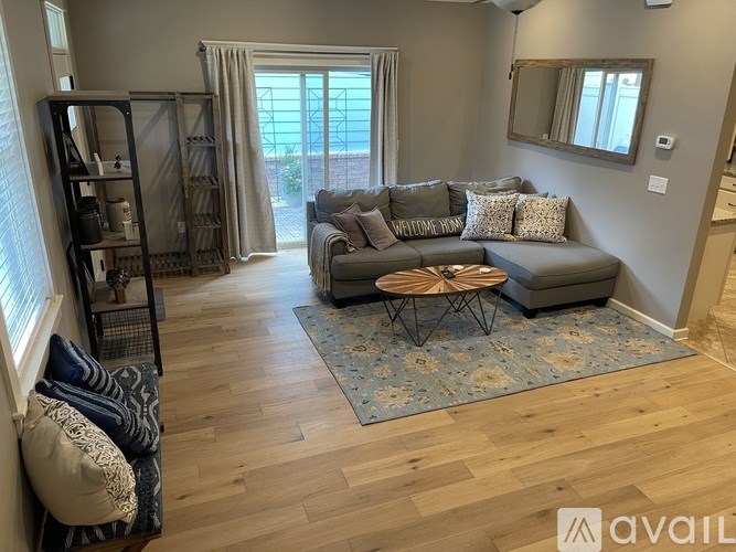 A living room with a grey couch and a wooden floor.