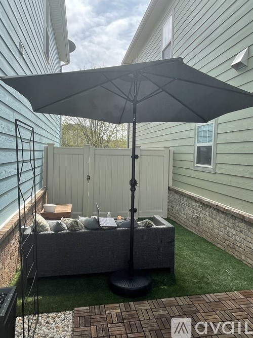 A patio with a grey couch and a black umbrella.
