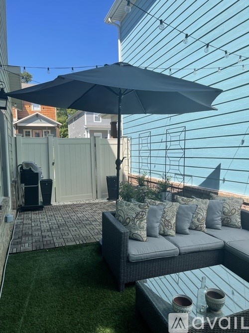 A patio with a grey couch and a white umbrella.