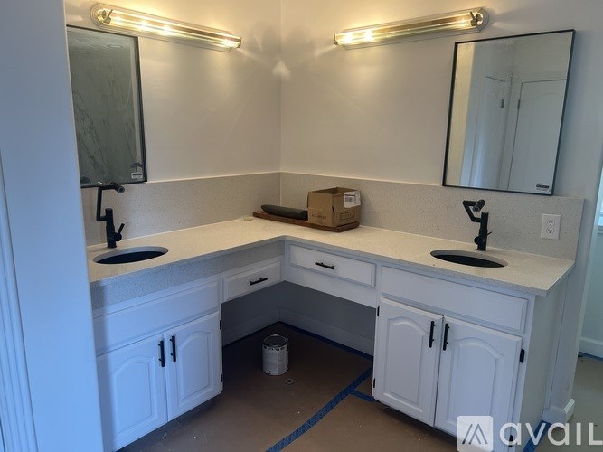 A white vanity with a sink and mirror is under a strip of lights.