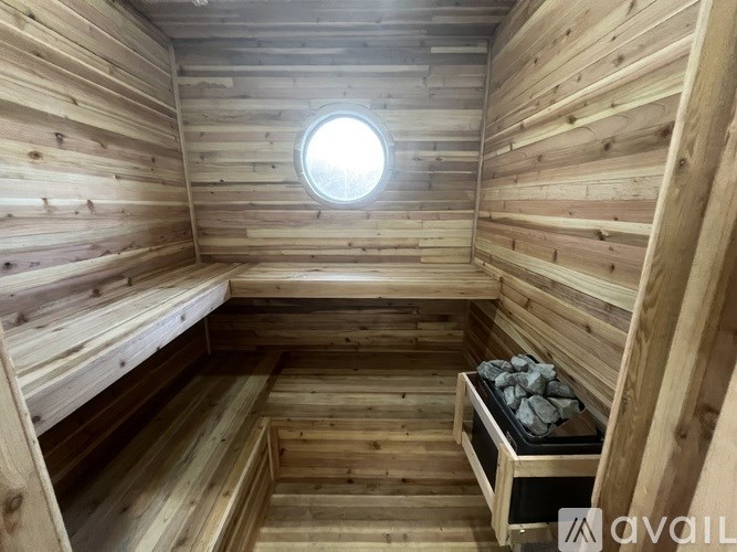 A wooden sauna with a round window and a stone bench.