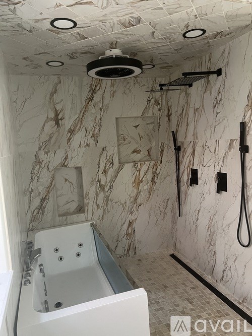 A bathroom with a marble wall and a white bathtub.