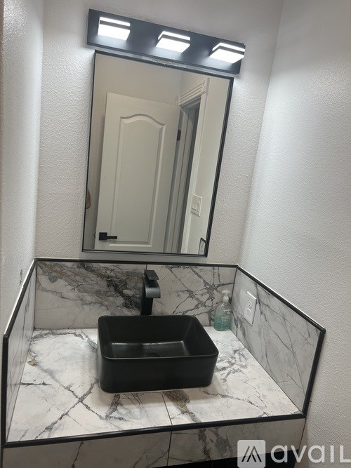 A bathroom sink with a marble countertop and a mirror above it.