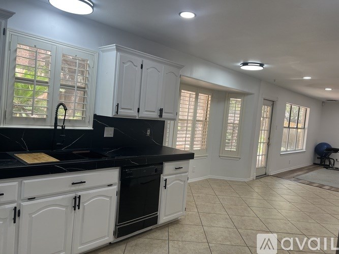 A kitchen with white cabinets and black countertops.