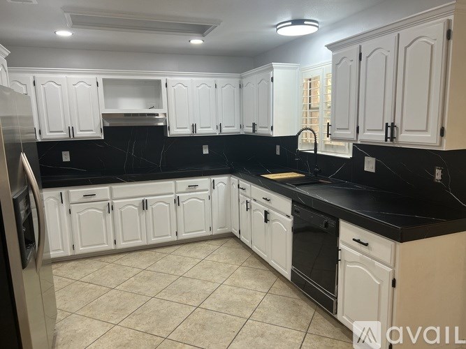 A kitchen with white cabinets and black countertops.