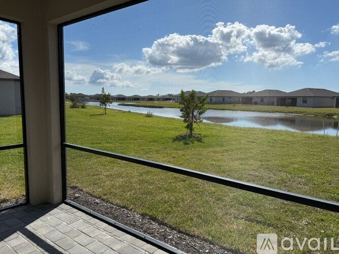 A view from a window looking out at a grassy field and a body of water.