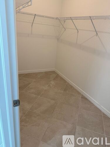A room with a tiled floor and a white wall with a metal rack on it.
